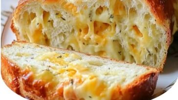 "Golden, freshly baked cheese bread with a crispy crust, oozing melted cheese from the center, sliced and served on a wooden board."