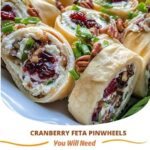 "Festive cranberry and feta cream cheese roll-ups with a swirl of red cranberries and white feta, wrapped in a tortilla, sliced into bite-sized pieces, and served on a platter."