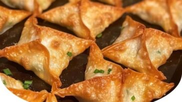 "Crispy baked crab rangoons with a golden-brown, crunchy exterior, stuffed with a creamy crab and cream cheese filling, served on a plate with dipping sauce."
