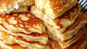 "Fluffy, golden flourless cottage cheese pancakes stacked on a plate, topped with fresh fruit and a drizzle of syrup."