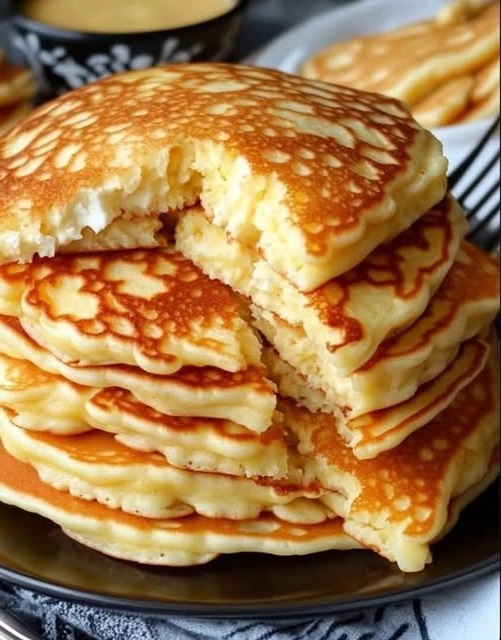 "Fluffy, golden flourless cottage cheese pancakes stacked on a plate, topped with fresh fruit and a drizzle of syrup."