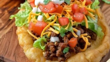 "Indian fry bread tacos with a soft, fluffy fry bread shell filled with seasoned meat, lettuce, and toppings."