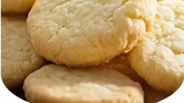 "Soft, golden melt-in-your-mouth butter cookies arranged on a plate, dusted with a light coating of sugar."