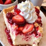 A warm, golden-brown strawberry cheesecake dump cake with a crumbly top, revealing layers of sweetened cream cheese, strawberry filling, and a buttery cake mix. The dish is garnished with fresh strawberries for a vibrant touch.