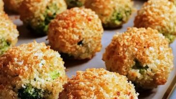 Crispy, golden-brown Cheesy Broccoli Bites arranged on a plate, with melted cheese and vibrant green broccoli visible inside, served with a dipping sauce on the side.