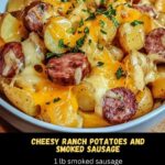 plate of cheesy ranch potatoes and smoked sausage, featuring golden, crispy potatoes topped with melted cheese, and slices of savory smoked sausage scattered throughout.