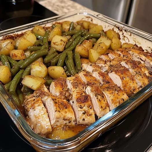 A plate of Easy Italian Chicken and Potatoes, featuring golden-brown roasted chicken thighs surrounded by tender, seasoned potatoes, garnished with fresh herbs.