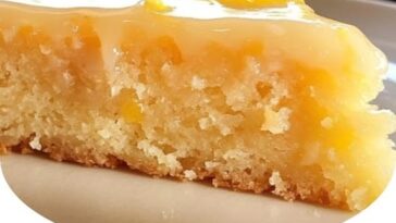 A slice of flourless ricotta, lemon, and almond cake on a white plate, topped with powdered sugar and a lemon zest garnish.