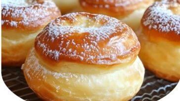 Fluffy and golden French breakfast puffs dusted with powdered sugar, sitting on a plate with a warm, inviting appearance.