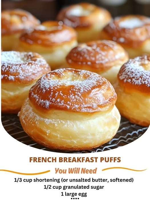 Fluffy and golden French breakfast puffs dusted with powdered sugar, sitting on a plate with a warm, inviting appearance.