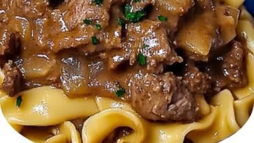 A hearty plate of French Onion Beef and Noodles, featuring tender beef, caramelized onions, and noodles in a rich, savory sauce, garnished with fresh herbs.