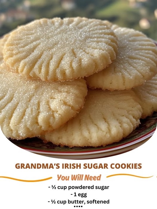 Close-up of a plate of homemade Irish sugar cookies dusted with sugar, shaped into delicate rounds, with a light golden-brown color.