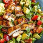 A fresh Grilled Chicken Avocado Salad with grilled chicken slices, creamy avocado, mixed greens, and vibrant vegetables, drizzled with a zesty dressing.
