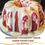 A freshly baked homemade strawberry cream cheese pound cake with a light pinkish hue, topped with slices of fresh strawberries and a creamy glaze.