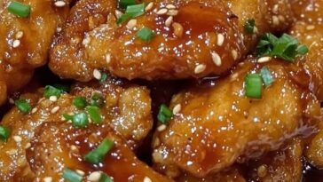 A plate of Honey Garlic Chicken, golden-brown and glazed with a sweet and savory honey garlic sauce, served with a side of vegetables.