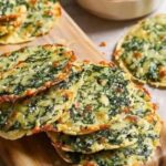 A close-up of Mediterranean Spinach and Feta Crisps, golden and crispy with visible spinach and crumbled feta, served as a savory snack.