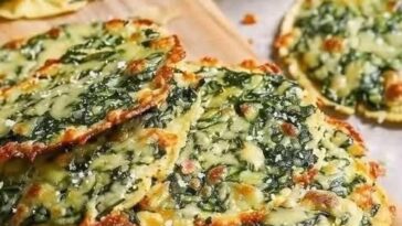 A close-up of Mediterranean Spinach and Feta Crisps, golden and crispy with visible spinach and crumbled feta, served as a savory snack.