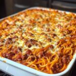 delicious, cheesy Million Dollar Spaghetti Casserole, with layers of pasta, rich marinara sauce, and melted cheese, served in a baking dish.