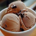 A scoop of Mocha Noir Dream Ice Cream with a rich blend of dark chocolate and coffee swirls, topped with chocolate shavings.