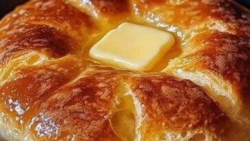 A golden, fluffy loaf of stovetop bread, sliced and displayed on a wooden cutting board, with a light, airy texture visible inside.