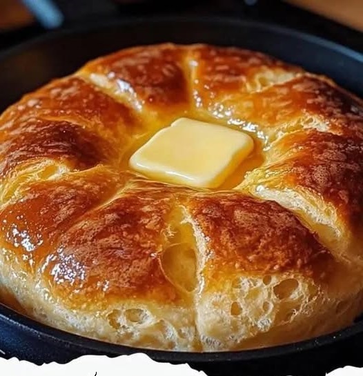 A golden, fluffy loaf of stovetop bread, sliced and displayed on a wooden cutting board, with a light, airy texture visible inside.