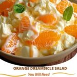 A creamy orange dreamsicle salad with orange segments, whipped cream, and a fluffy texture, served in a bowl.