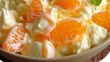 A creamy orange dreamsicle salad with orange segments, whipped cream, and a fluffy texture, served in a bowl.