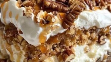 A slice of pecan pie lasagna with layers of creamy filling, pecans, and a golden crust, topped with whipped cream.