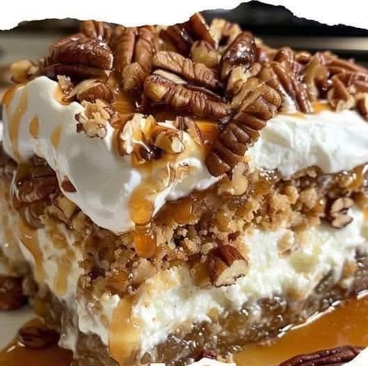 A slice of pecan pie lasagna with layers of creamy filling, pecans, and a golden crust, topped with whipped cream.