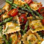 Delicious ravioli tossed with fresh tomatoes, asparagus, garlic, and aromatic herbs, served as a vibrant and healthy Italian-inspired dish.