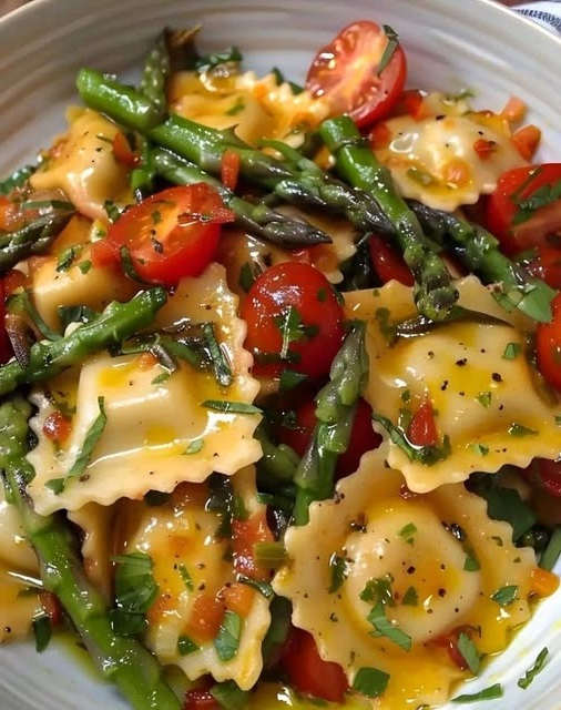Delicious ravioli tossed with fresh tomatoes, asparagus, garlic, and aromatic herbs, served as a vibrant and healthy Italian-inspired dish.