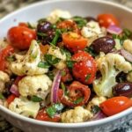 A vibrant Sicilian cauliflower salad with roasted cauliflower, olives, capers, tomatoes, and fresh herbs, drizzled with olive oil.