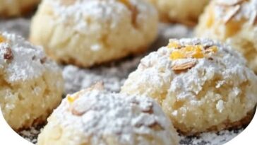 A plate of soft Italian almond cookies, dusted with powdered sugar and garnished with whole almonds, showcasing their delicate texture and light golden color.