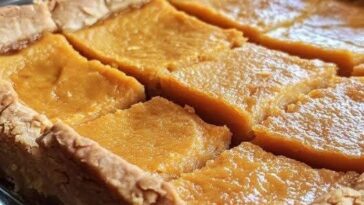 A plate of Sweet Potato Pie Bars with a golden-brown crust and a smooth, spiced sweet potato filling, topped with a dusting of cinnamon.