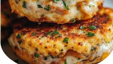 Golden-brown tuna melt patties with melted cheese on top, garnished with fresh herbs, placed on a plate