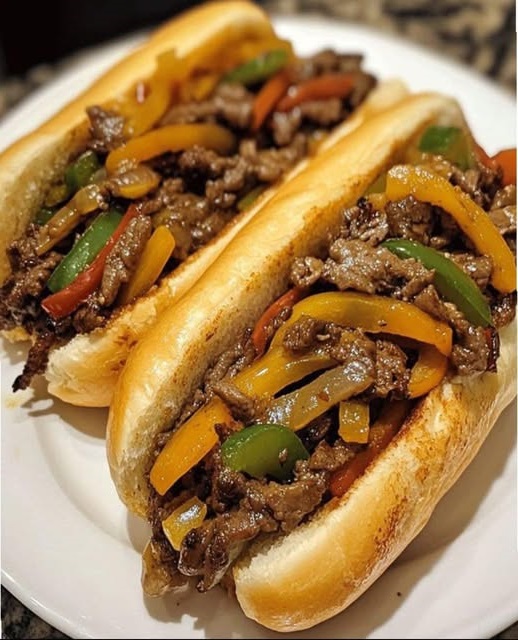 A Philly-style steak and pepper hoagie sandwich with thinly sliced steak, sautéed peppers and onions, melted cheese, all nestled in a toasted hoagie roll.