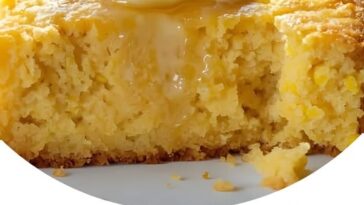 A warm slice of Amish Sour Cream Cornbread on a plate, with a golden crust and a moist, soft interior.
