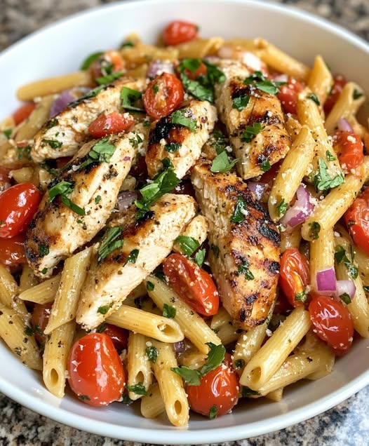 bowl of pasta topped with grilled chicken, fresh tomatoes, basil, and drizzled with balsamic glaze.