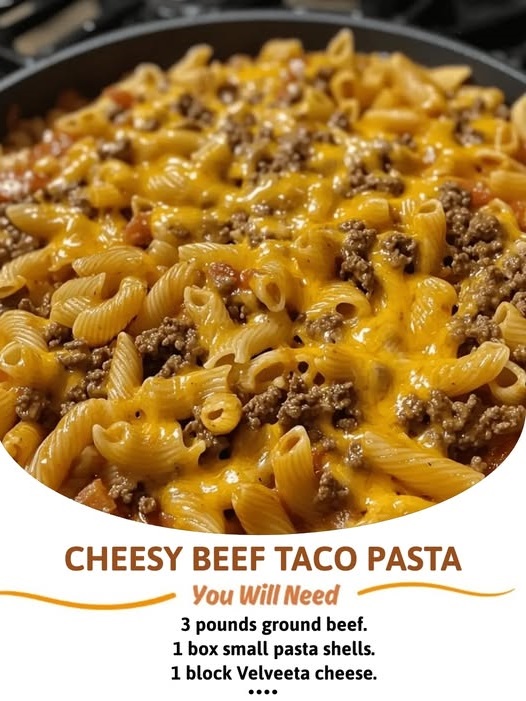 Cheesy beef taco pasta in a skillet, topped with melted cheese and garnished with fresh herbs.