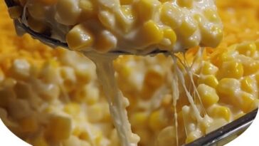Baked cream cheese corn casserole in a dish, golden and bubbly on top with visible corn kernels and melted cheese.