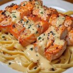 Creamy garlic butter salmon pasta with flaked salmon, linguine, and fresh herbs, served in a white bowl.