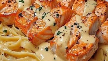 Creamy garlic butter salmon pasta with flaked salmon, linguine, and fresh herbs, served in a white bowl.