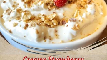 Bowl of creamy strawberry shortcake dip topped with crushed golden cookies and fresh strawberry slices, surrounded by dippers like vanilla wafers and graham crackers.
