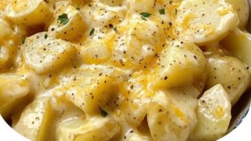 Crockpot filled with creamy, cheesy potatoes topped with melted cheese and fresh herbs.