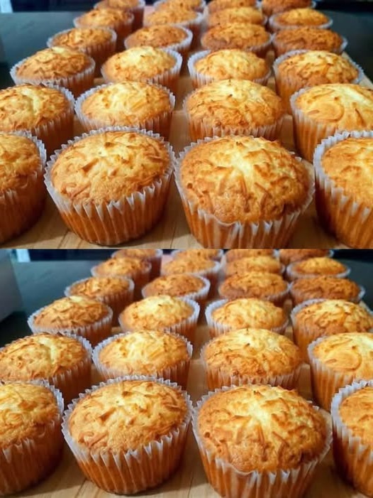 A batch of golden-brown cupcake cheese muffins with a fluffy texture and a cheesy topping, arranged on a wooden surface.