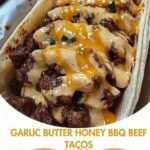 Garlic butter honey BBQ beef tacos in soft tortillas, filled with shredded beef, drizzled with sauce, and topped with fresh herbs and slaw.