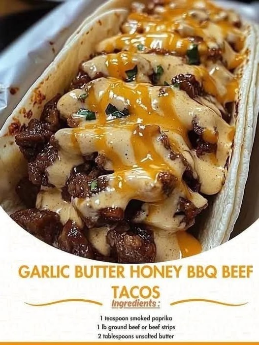 Garlic butter honey BBQ beef tacos in soft tortillas, filled with shredded beef, drizzled with sauce, and topped with fresh herbs and slaw.