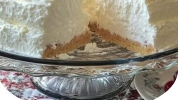 A slice of Heaven on Earth Cake with layers of fluffy cake, whipped cream, and fruit, topped with a light dusting of sugar.