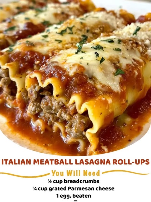 Italian meatball lasagna roll-ups on a white plate, covered in marinara sauce and melted cheese, garnished with fresh basil.