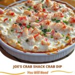 Creamy crab dip in a skillet, topped with melted cheese and served with toasted bread slices.